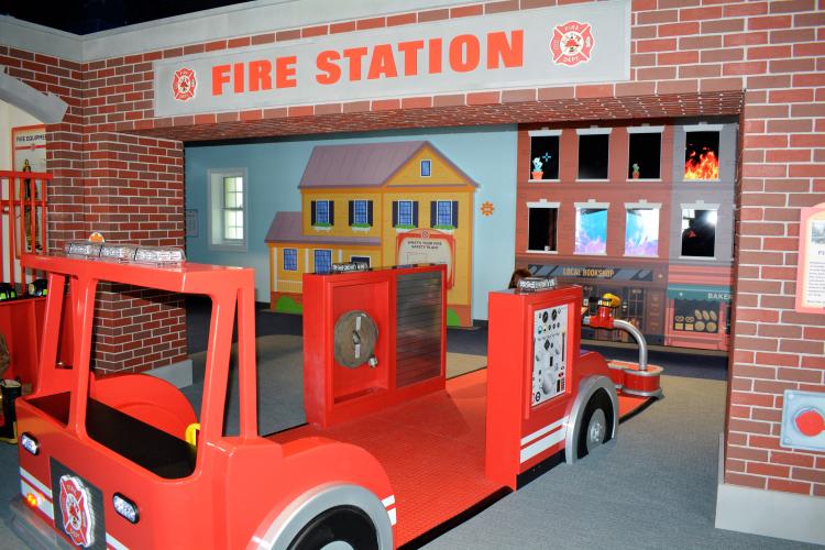 Wooden fire truck positioned under fire station sign