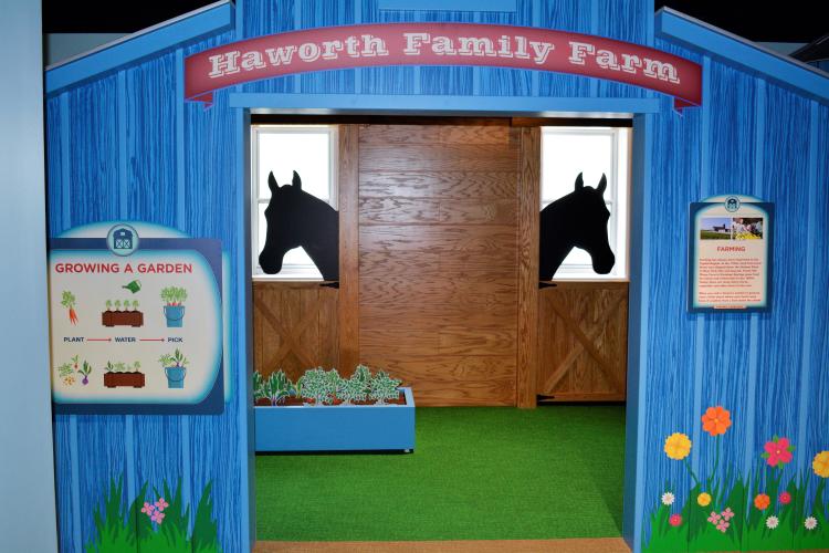 Farm exhibit featuring blue barn and horse silhouettes