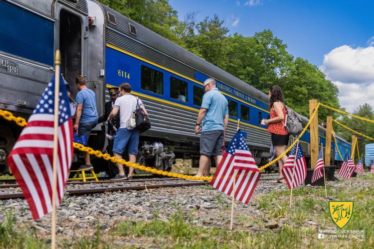 Passengers boarding train with American flags in foreground