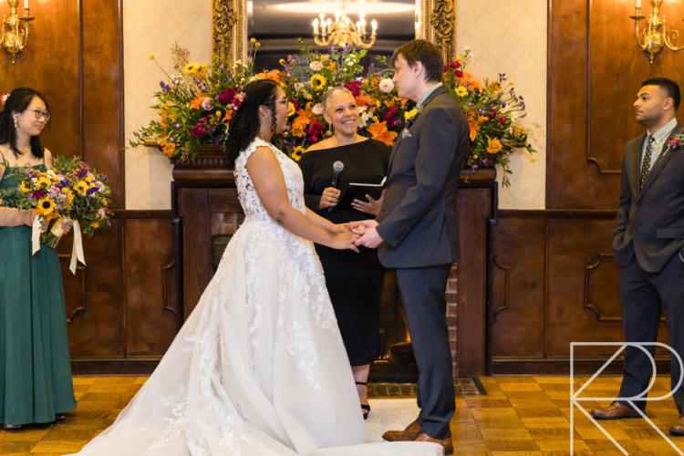 Wedding officiant performing a ceremony with bride and groom holding hands