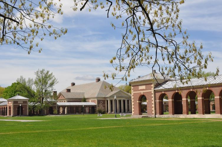 State Park buildings across main lawn with blue sky and white clouds, large branch with blossoms across the top of the photo