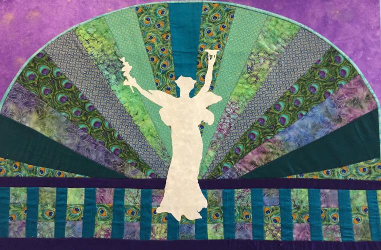 Colorful quilt on purple background with white Spirit of Life in center