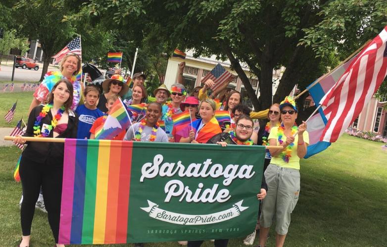 Group of people carrying a Saratoga Pride banner and American flag