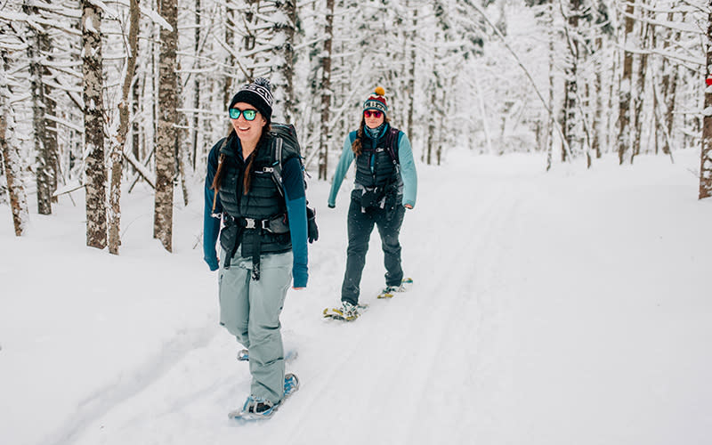 Two women snowshoeing in the woods