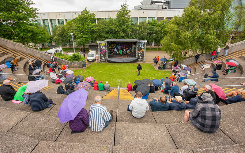 People sitting around the amphitheatre in the rain,