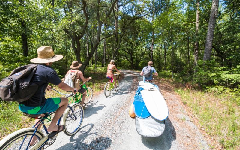 People Biking And Bringing Surfboards To Sandbridge Beach In Virginia Beach, VA