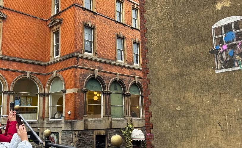 People looking at Banksy's 'Well Hung Lover' on Park Street, central Bristol