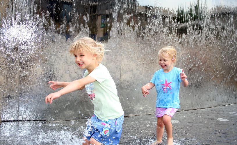 Children splashing in water feature in Millennium Square on Bristol's Harbourside - credit Tamany Baker