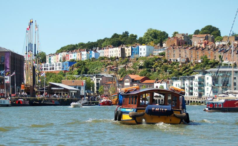 A Bristol Ferry Boat sailing eastwards on Bristol's Harbourside, with the SS Great Britain and colourful houses of Cliftonwood in the background - credit Visit West