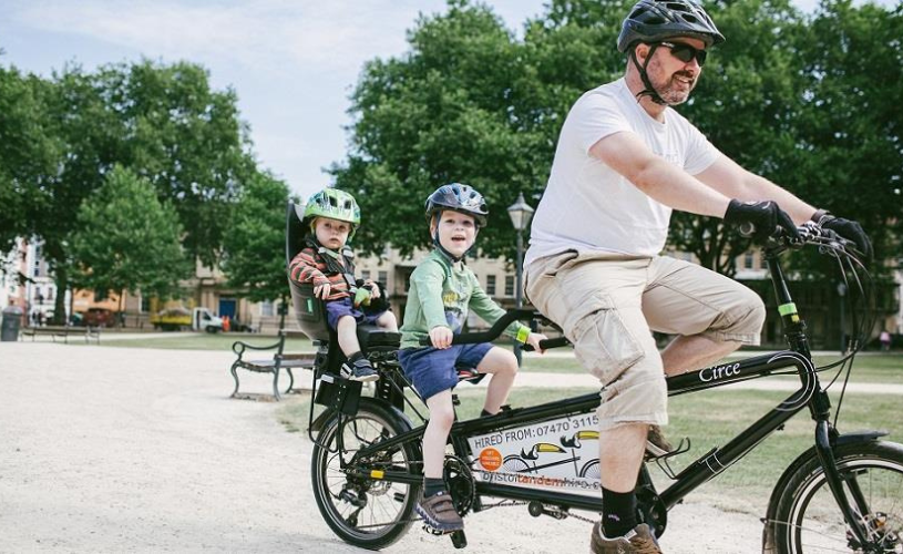 A family cycling on a tandem on Queen Square in central Bristol - credit Bristol Tandem Hire
