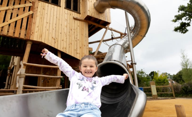 A small child sat at the bottom of a large metal slide