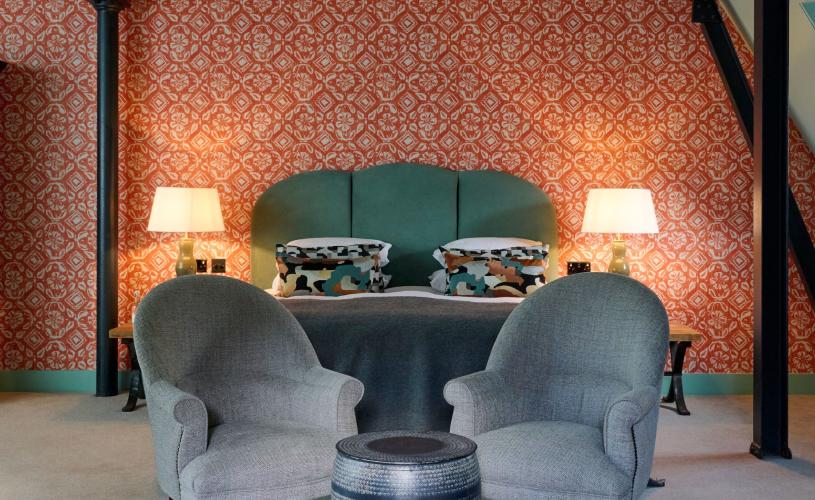 Bedroom with pink walls, large bed and two comfy chairs at Hotel Du Vin in central Bristol - credit Hotel Du Vin