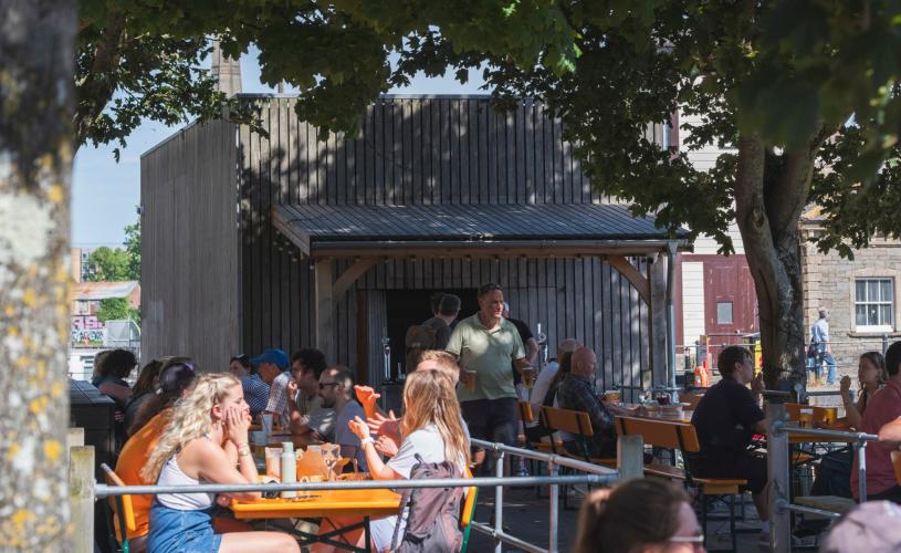 People sitting on the outdoor tables at the Arnolfini Cafe Bar in summer - credit Arnolfini