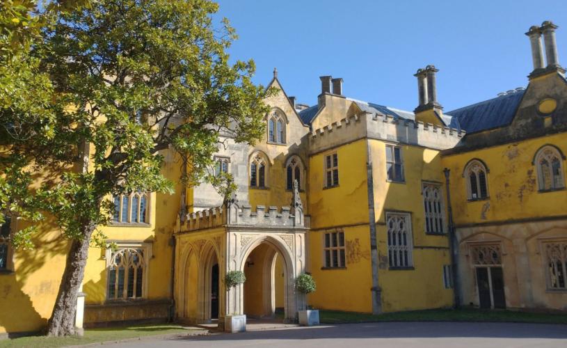 The entrance to Ashton Court mansion. A yellow exterior with various windows placed around the walls. A tree stands on the left side of the mansion - credit Bristol Design