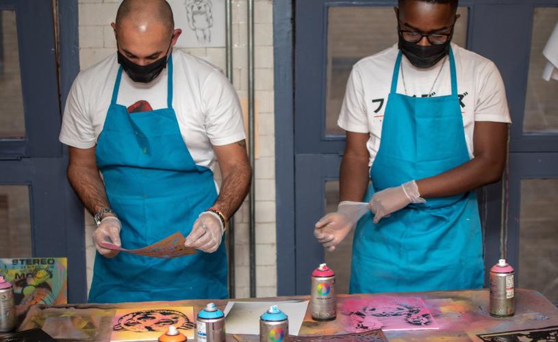 Two people spray painting a canvas Graft Bristol - credit Yuup