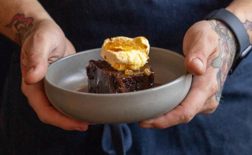 Person holding a bowl of sticky toffee pudding - credit BANK