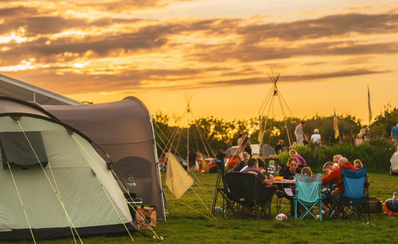 A family sat in camping chairs in a field - Credit Mendip Activity Centre
