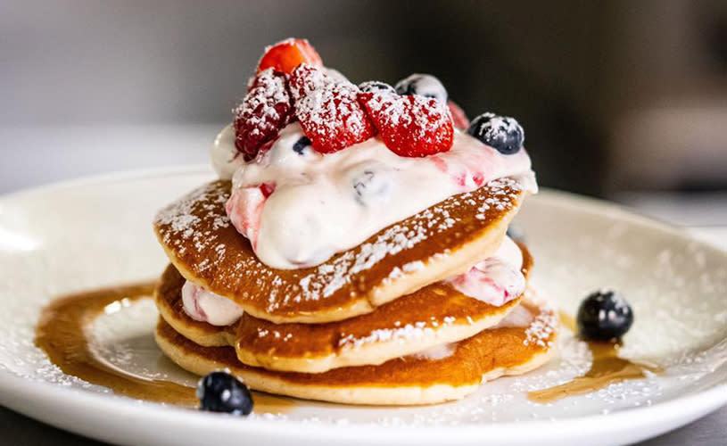 A stack of pancakes with cream and berries ontop - Credit Browns Brasserie