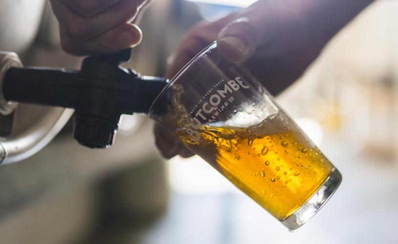Person pouring a pint of beer from a cask - credit Butcombe Brewery