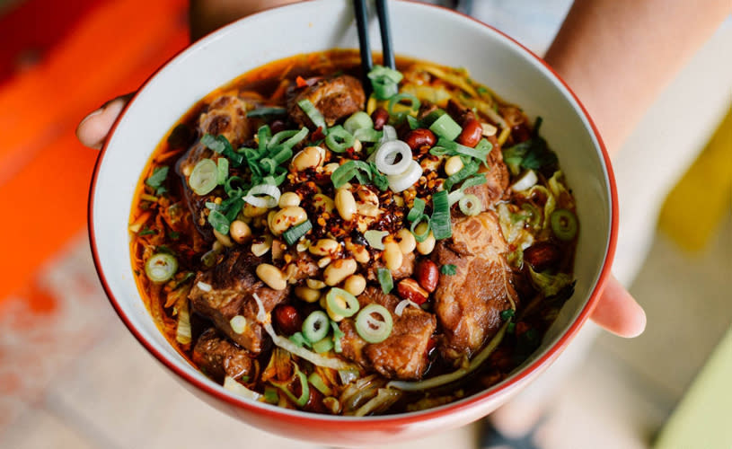 Person holding bowl of spicy noodles - credit Chilli Daddy