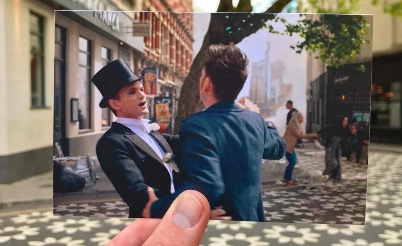 A view of Clare Street in Bristol's Old City, with a hand holding a photograph of actors David Tennant & Neil Patrick Harris filming one of the 2023 Doctor Who specials in the same spot - credit Logan Walker