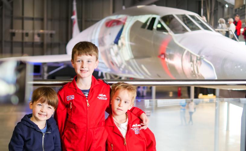Three young brothers standing in front of the Concorde Alpha Foxtrot supersonic airliner inside the Concorde Hangar at Aerospace Bristol - credit Aerospace Bristol