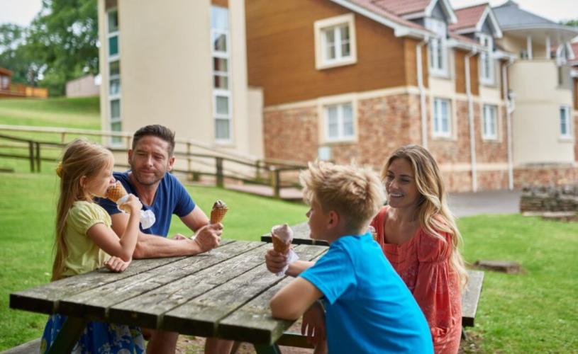 A fmaily eating ice cream on a bench outside Wookey Hole hotel - Credit Wookey Hole