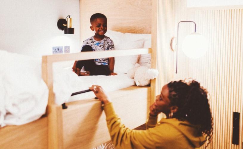 A young on a bunk bed with an adult female stood next to the bed - Credit Mollie's Motel and Diner