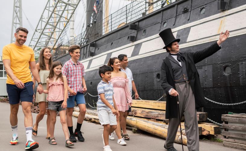 A family walking with Mr Brunel alongside the SS Great Britain in the Great Western Dockyard, Bristol - credit Brunel's SS Great Britain