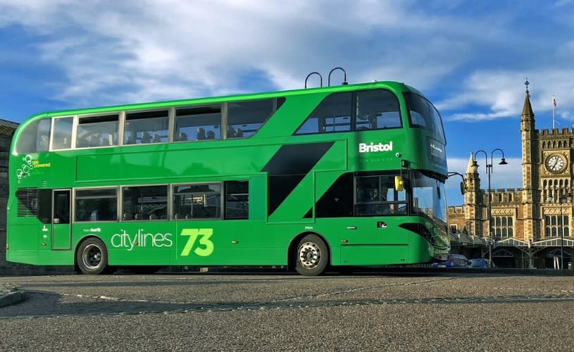 A green double decker bus outside Bristol Temple Meads railway station