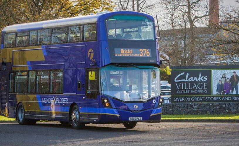 A purple and beige-coloured Mendip Explorer 376 bus parked at Clarks Village in Street, Somerset - First Bus