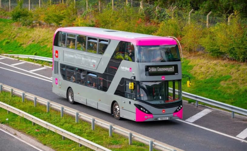 A grey and pink double decker bus on a dual carriageway