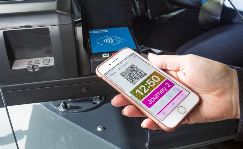 A hand holding a phone under a ticket scanner