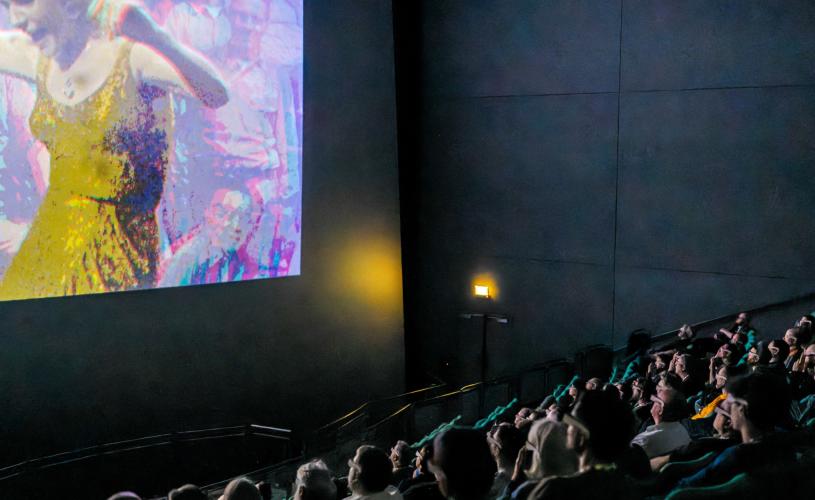 People sat in audience watching a film in large cinema