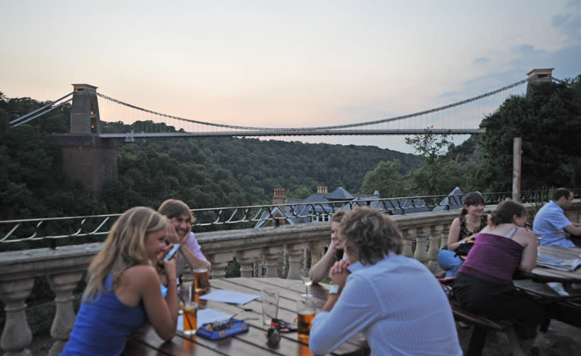 People sat at tables on terrace overlooking the Clifton Suspension Bridge at dusk - credit The White Lion