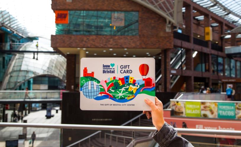Hand holding a Love Bristol Gift Card shopping voucher in Cabot Circus, central Bristol - credit Bristol BIDs