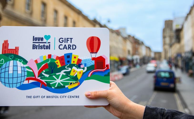 Hand holding a Love Bristol Gift Card shopping voucher in Park Street, central Bristol - credit Bristol BIDs