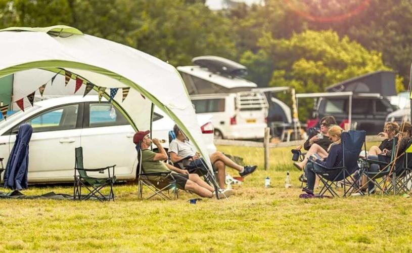 A family sat in camping chairs in a field - Credit Mendip Activity Centre