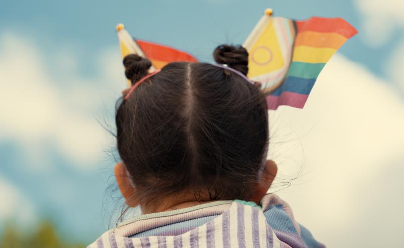 A small child at Bath Pride with various Pride flags