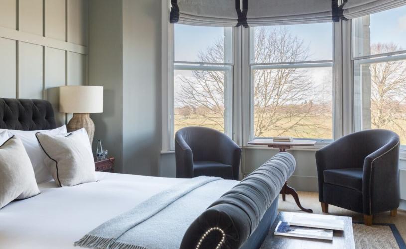 A large bedroom with 2 grey chairs at Number 38 Clifton - Credit XCVI