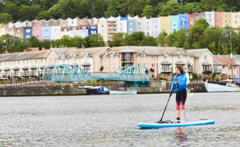 Person stand up paddleboarding in harbour