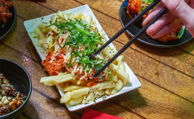 Kimchi fries and other dishes on table - credit Seven Lucky Gods
