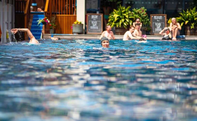 A lady wearing a grey swimming cap swimming at Bristol Lido