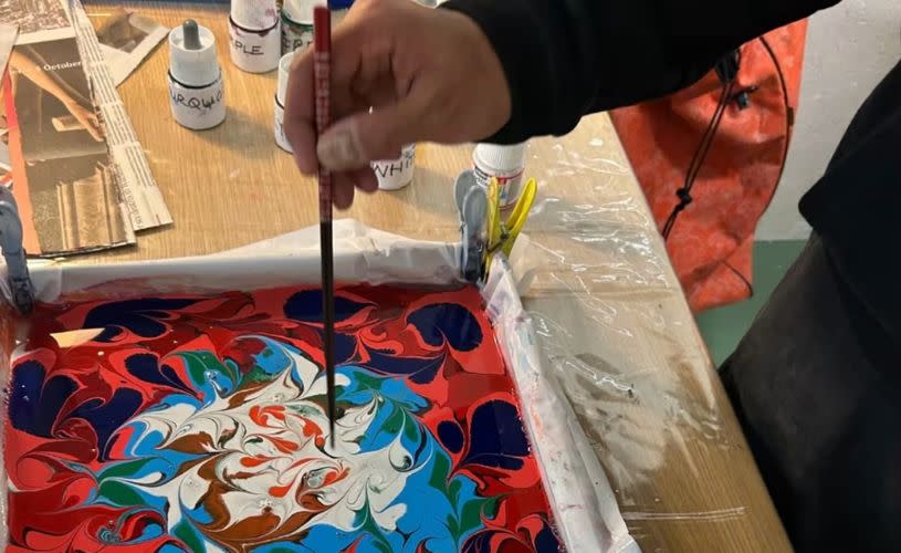 A water tray filled with paint that is being swirled