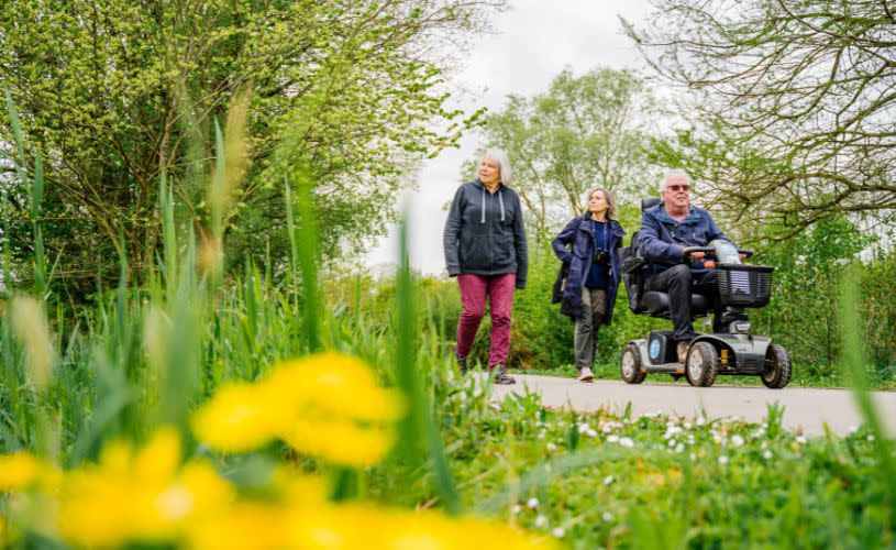 2 people walking around WWT Slimbridge with one person in a mobility scooter