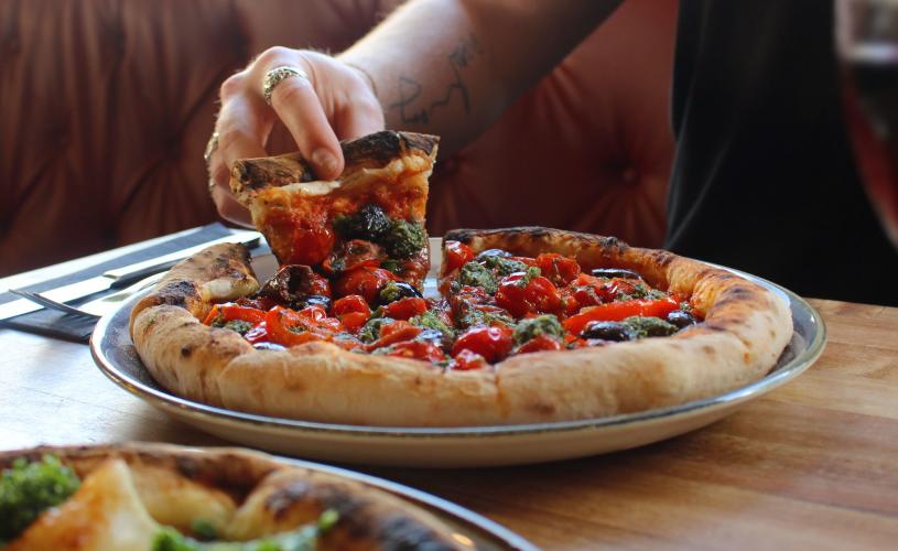 Person pulling a slice of vegan pizza - credit Cafe Napolita