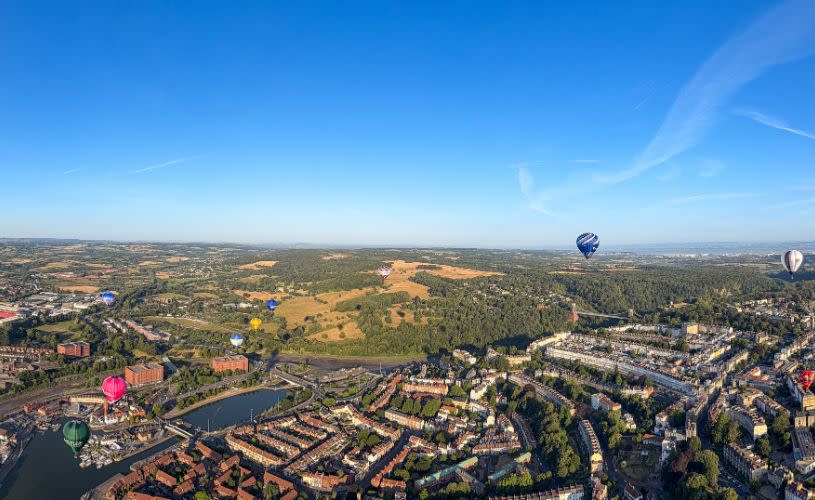 A panoramic ariel view of Bristol with multiple hot air balloons