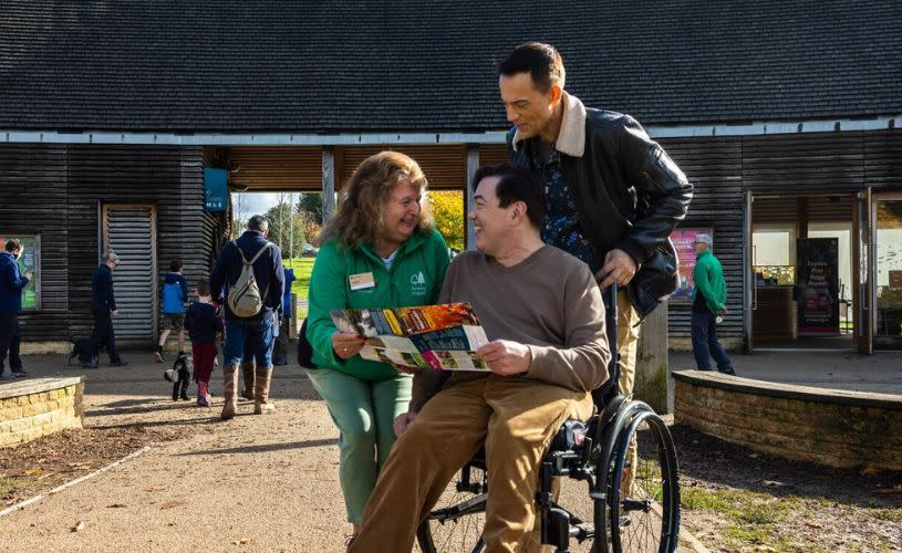 A wheelchair user being shown a map by a Westonbirt volunteer
