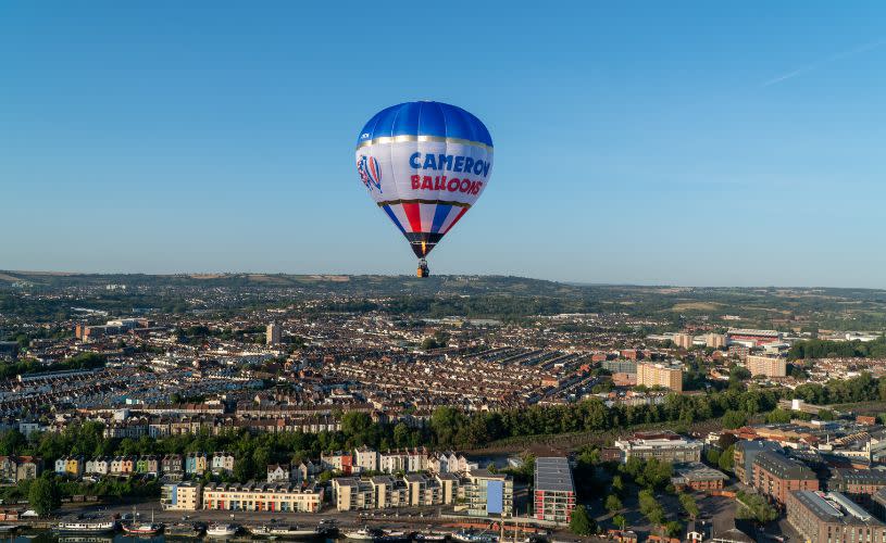 A blue and white Cameron Balloon flying over Bristol