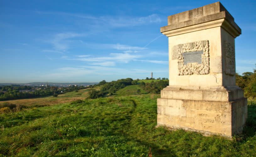 The base of a 4-sided stone obelisk on the grassland of Stoke Park Estate